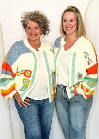 Two women modeling a colorful sweater cardigan