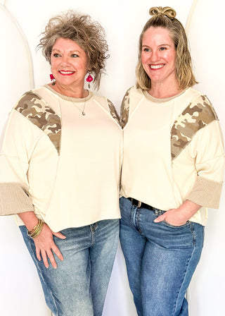 Cream knit colorblock top with camo print shoulder panels, ribbed taupe sleeves and cuffs, and a crew neckline.