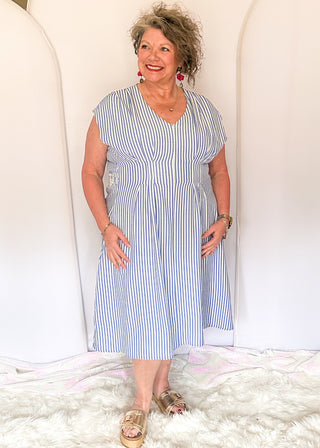 Sleeveless dress with vertical blue and white stripes. v neck and smocked waist