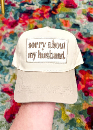 Cream snap back ball cap with a kahki bill and matching embroidered patch “sorry about my husband.” 