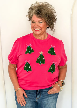 woman wearing a short sleeve pink top with embellished mini trees.