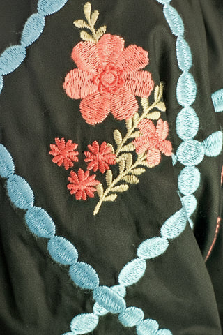 close up of black midi dress with embroidered puff sleeves and a smocked bodice