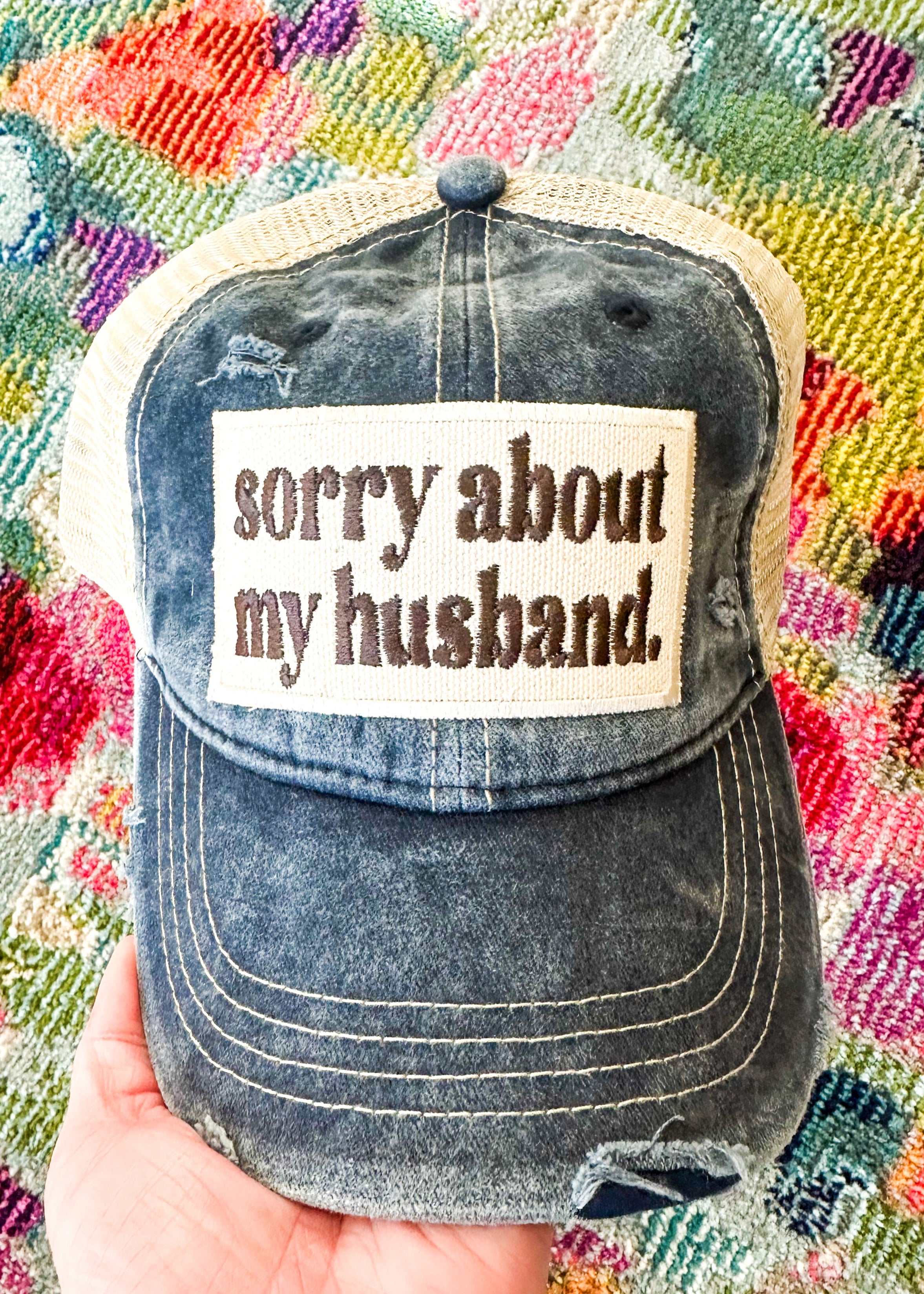 "sorry about my husband" embroidered patch in brown on navy and khaki snapback hat.