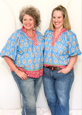 Bright blue 3/4 sleeve top with floral pattern, smocked collar with matching coral floral neckline and hem. 