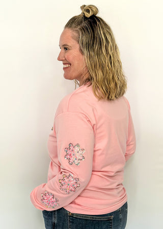 Light pink long sleeve top with beaded ‘MERRY’ lettering across the chest and sequin and beaded snowflakes on the sleeves. 