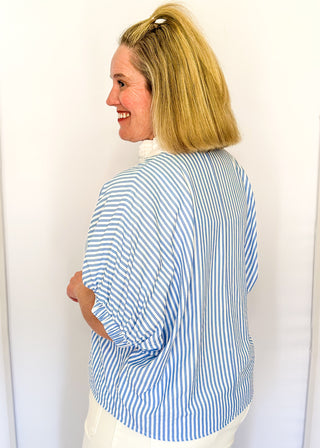 Striped seersucker top in light blue and white with short sleeves, relaxed fit, and split neckline.