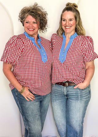 Women’s gingham blouse with decorative buttons and statement neckline detail.