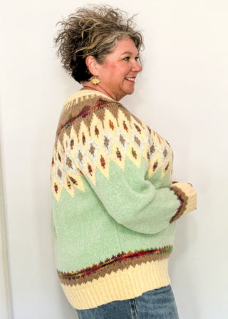 side view of woman modeling a cozy long sleeve sweater with geometric pops of color with a cream and light blue base
