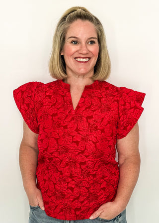 woman wearing red jacquard flutter sleeve blouse with a floral pattern