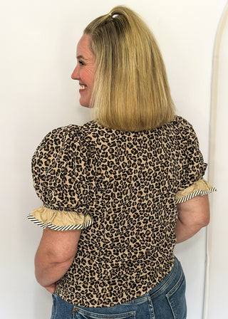 Leopard print blouse with ruffle neckline, puff sleeves, and striped trim.