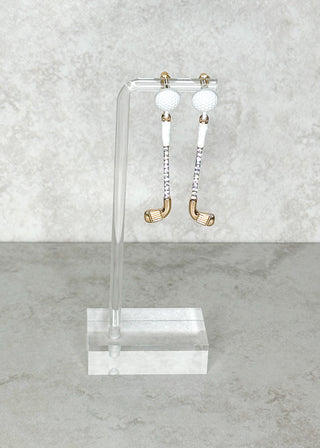 Pair of golf club shaped post back earrings on a clear stand against a gray background