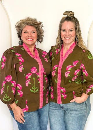 pink florals on brown long sleeve top with shades of pink ruffle around collar and down the front - button up