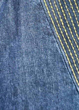 close up of women's dark blue denim dress featuring statement puff sleeves and contrast stitched detailing around the neckline.