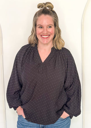 woman in black bubble hem long sleeve top with white dots.