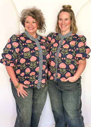Navy floral puff sleeve blouse with pink oversized floral print and striped contrast trim along the neckline and front placket.