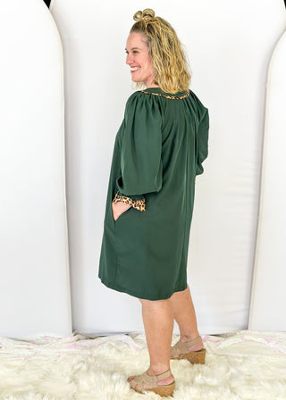 Knee length dark green dress with leopard detail around chest.  3/4 puff sleeve, split neckline, pockets. 