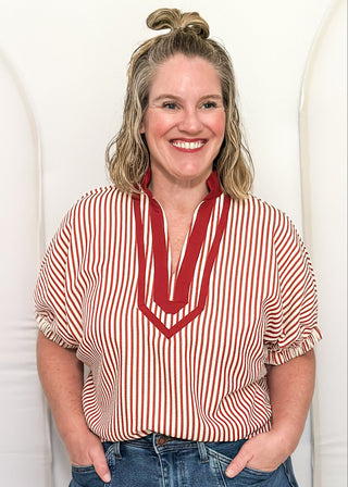 Woman wearing a brick and cream striped dolman-sleeve top with contrast trim, styled for a casual and relaxed fit.