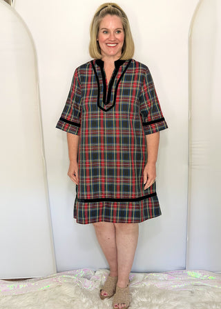woman wearing a navy plaid tunic dress with three-quarter sleeves and black trim details.