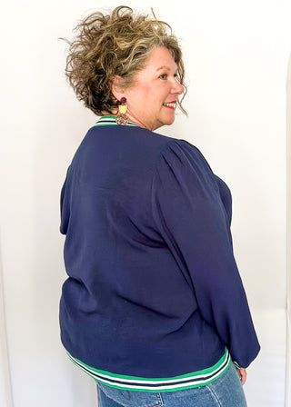 Navy long-sleeve top with green-and-white striped trim at neckline, cuffs, and hem.