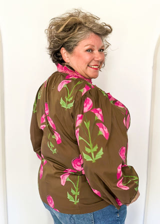 pink florals on brown long sleeve top with shades of pink ruffle around collar and down the front - button up