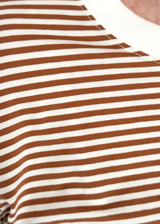 Close-up of a brown and white striped shirt with a brand logo.