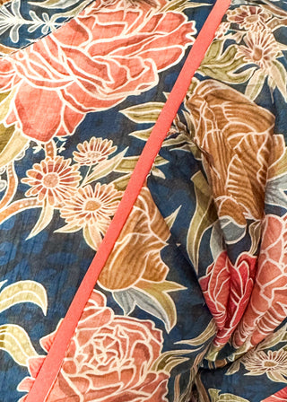 Short puff sleeve navy floral top. Florals are terracotta and coral.  V-neck with coral piping detail on chest.