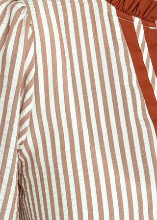 Close up of cinnamon-brown striped blouse with a split neckline, contrast trim, and 3/4 sleeves.