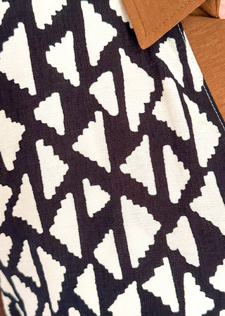 Close-up of a black and white geometric patterned fabric with a brown leather-like corner detail.