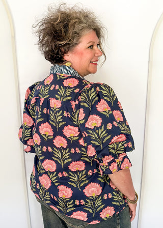 Navy floral puff sleeve blouse with pink oversized floral print and striped contrast trim along the neckline and front placket.