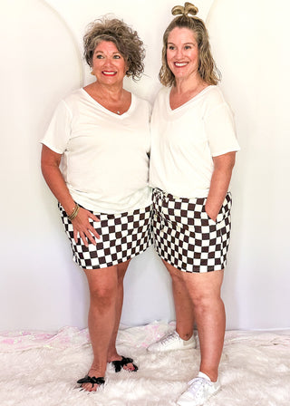Two women wearing checkered skorts with built-in shorts with a white tees.
