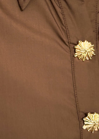 Close up of brown midi dress with decorative gold snaps.