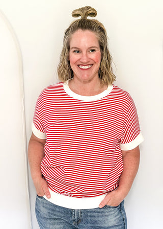 Woman wearing a red and white striped shirt and blue jeans against a white background