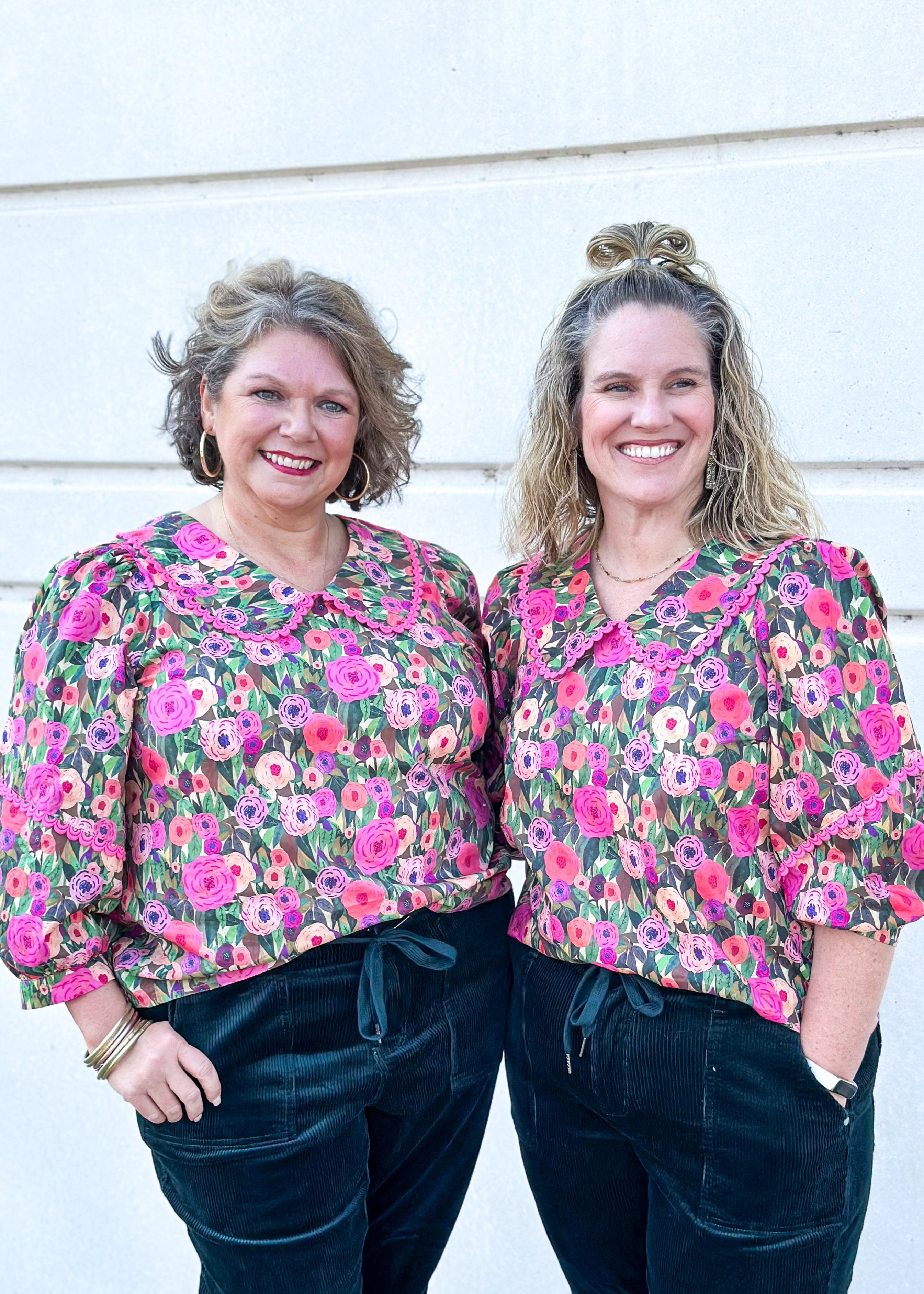 green watercolor background with shades of pink flowers- bib collar trimmed in rick rack and rick rack around the 3/4 sleeve