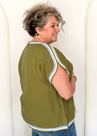 women wearing olive green top with cap sleeves and crew neckline, styled with jeans.