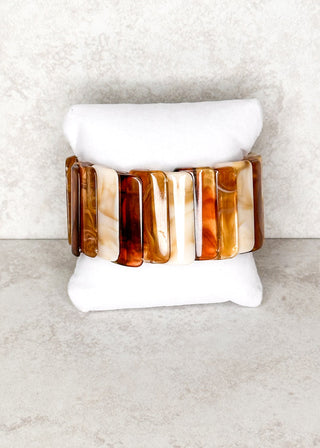 Resin bracelet in brown and creams displayed on a stand 