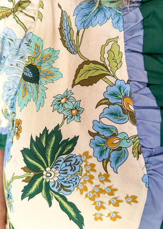 light blue and dark green botanicals on an ecru background.  Short ruffle sleeves, v-neck ruffle collar.  