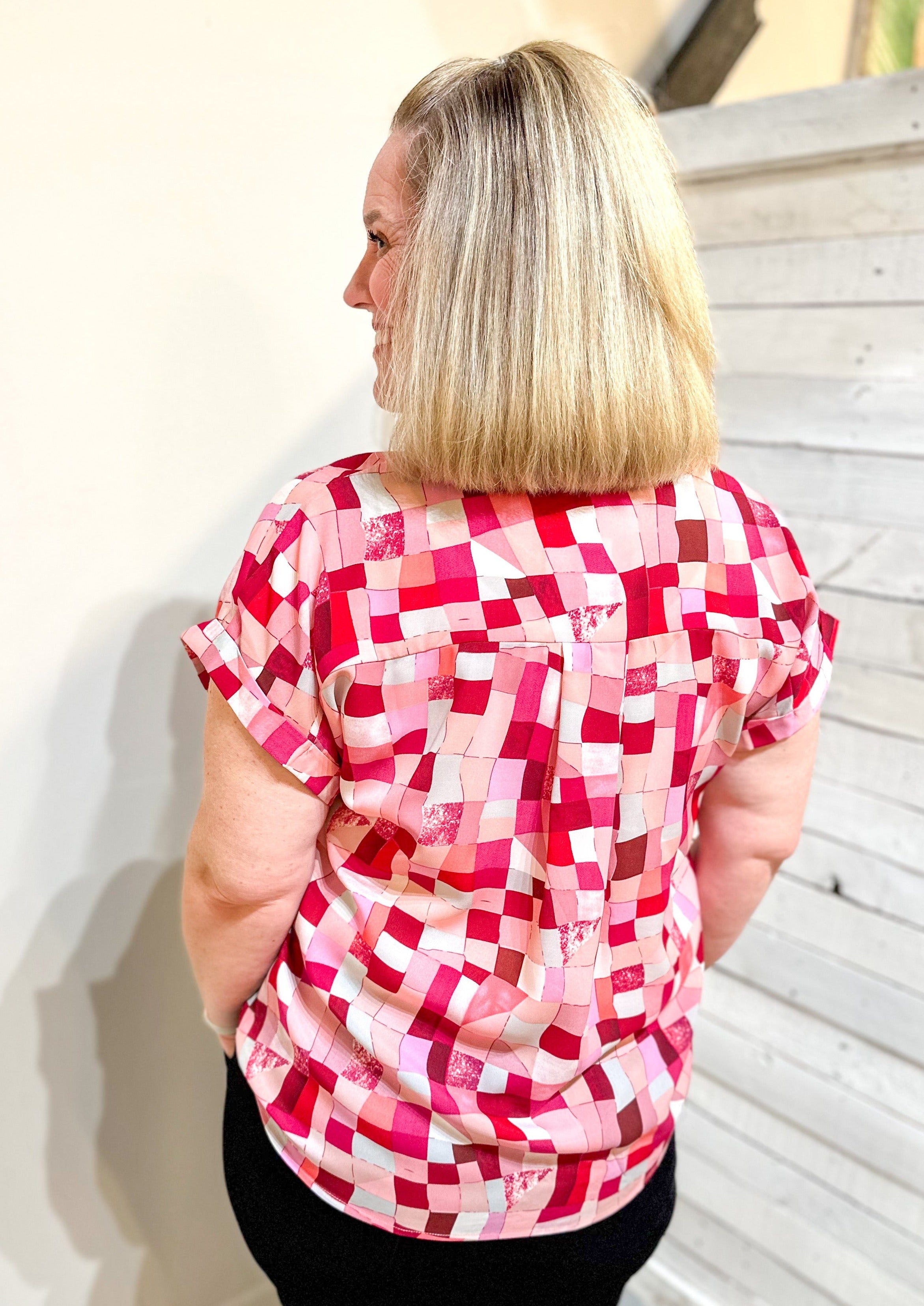 Back view of V-neck top with a drop shoulder sleeve. The pattern is an abstract and geometric mix of white, light pinks and dark pinks.