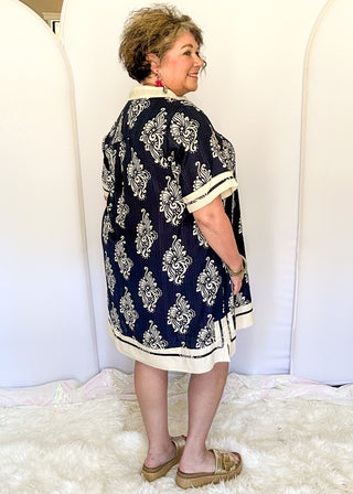 Navy printed short dress with cream contrast trim on the neckline, sleeves, and hem