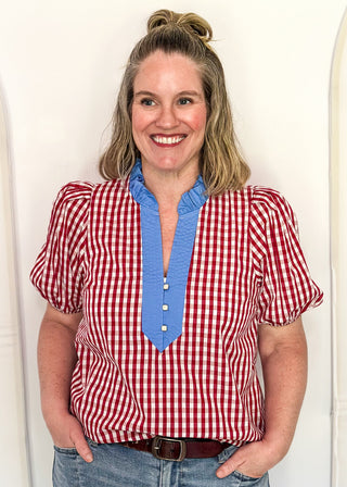 Women’s gingham blouse with decorative buttons and statement neckline detail.