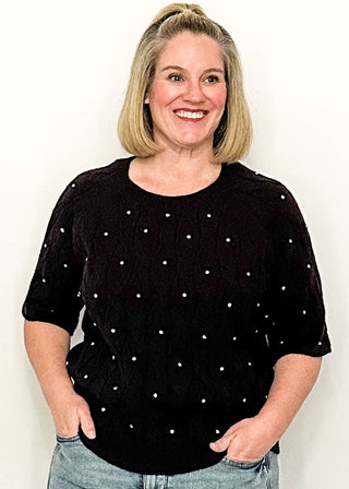 woman wearing black sweater with rhinestones, paired with jeans