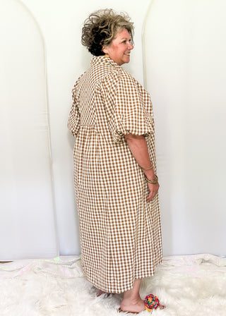 Woman wearing long brown gingham dress with short sleeves