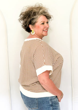 Woman wearing a striped shirt and jeans against a white background