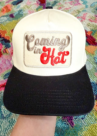 Snap-back canvas hat with black bill.  Embroidered patch "Coming in" (gray), "Hot" (Red)