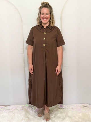 Woman wearing short sleeve, collared, Brown midi dress with decorative gold snaps.