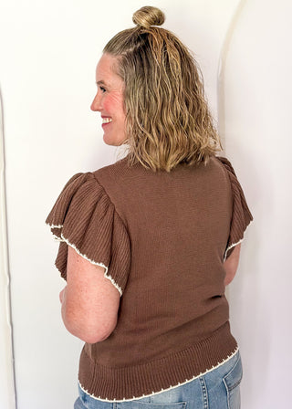 woman wearing brown short sleeve sweater with bird. 