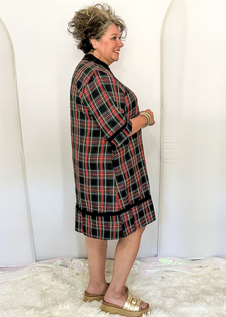 side view of woman wearing a navy plaid tunic dress with three-quarter sleeves and black trim details.