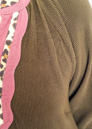close up of brown ribbed v-neck dress with pink scallop trim and leopard print contrast. 