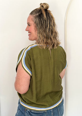 women wearing olive green top with cap sleeves and crew neckline, styled with jeans.