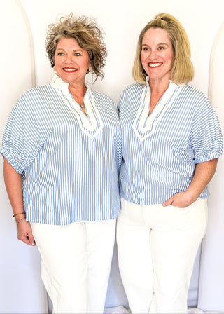 Striped seersucker top in light blue and white with short sleeves, relaxed fit, and split neckline.