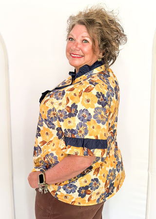 Bold Navy and golden blooms on this short sleeve top with navy ruffle detail on the sleeves, collar and 1/2 way down the front. Buttons up the front.